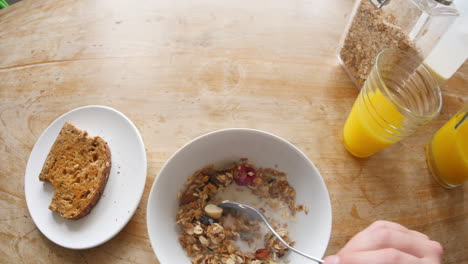 point of view of man eating cereal,toast  and drinking juice