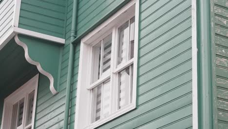 close up of a green wooden building with a white window