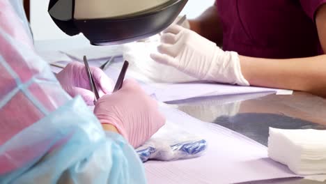 Two-nurses-working-to-prepare-hair-cell-cultures-using-forceps,-medical-instruments