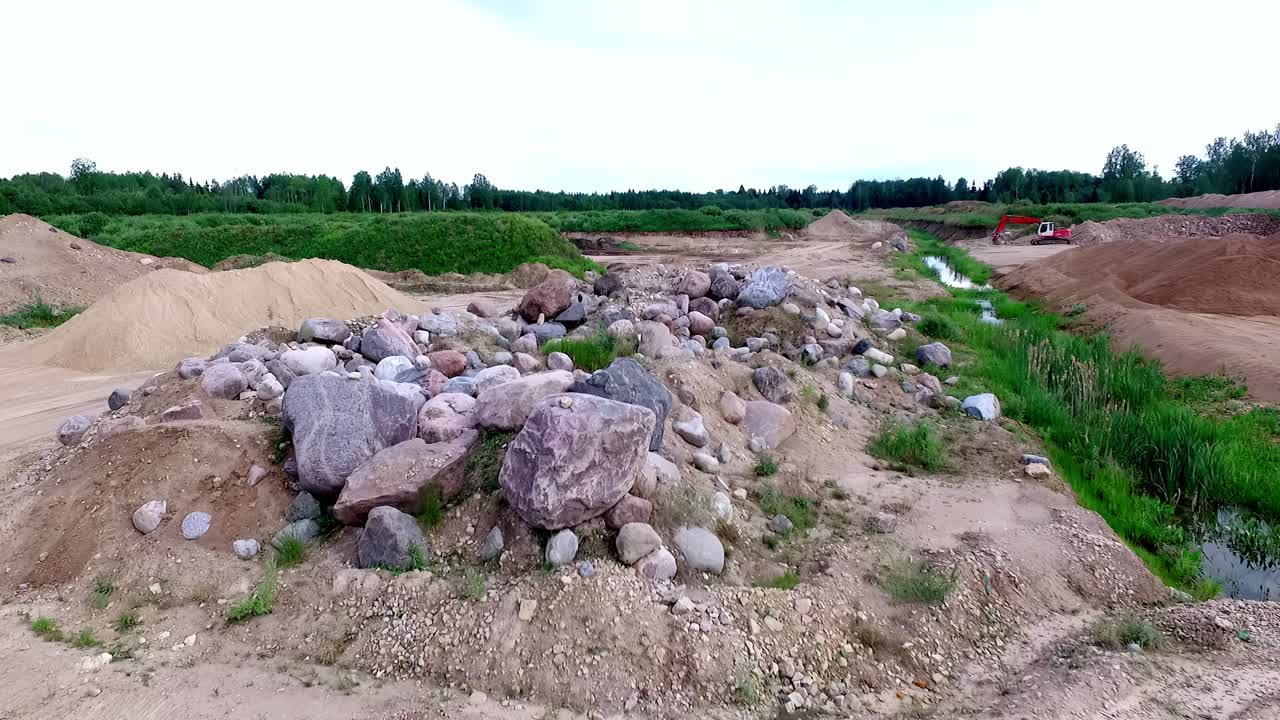 Large rocks and gravel piles next to industrial excavation and sand mounds