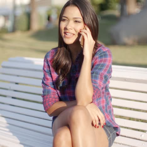 woman using cell phone on park bench