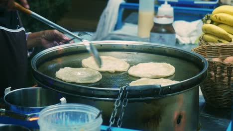 4k cinematic cooking footage of a thai chef preparing a traditionnal thai dessert called roti in a street market in thailand