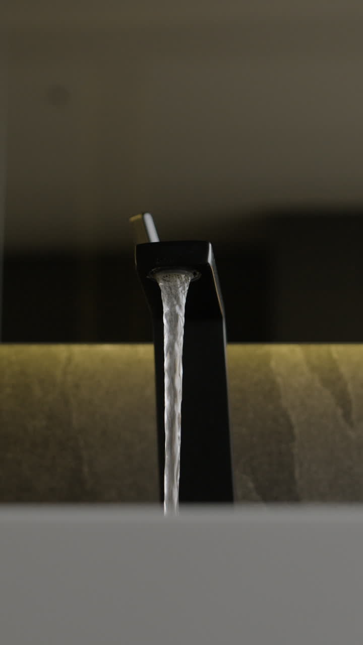 Close-up of a black faucet with water running