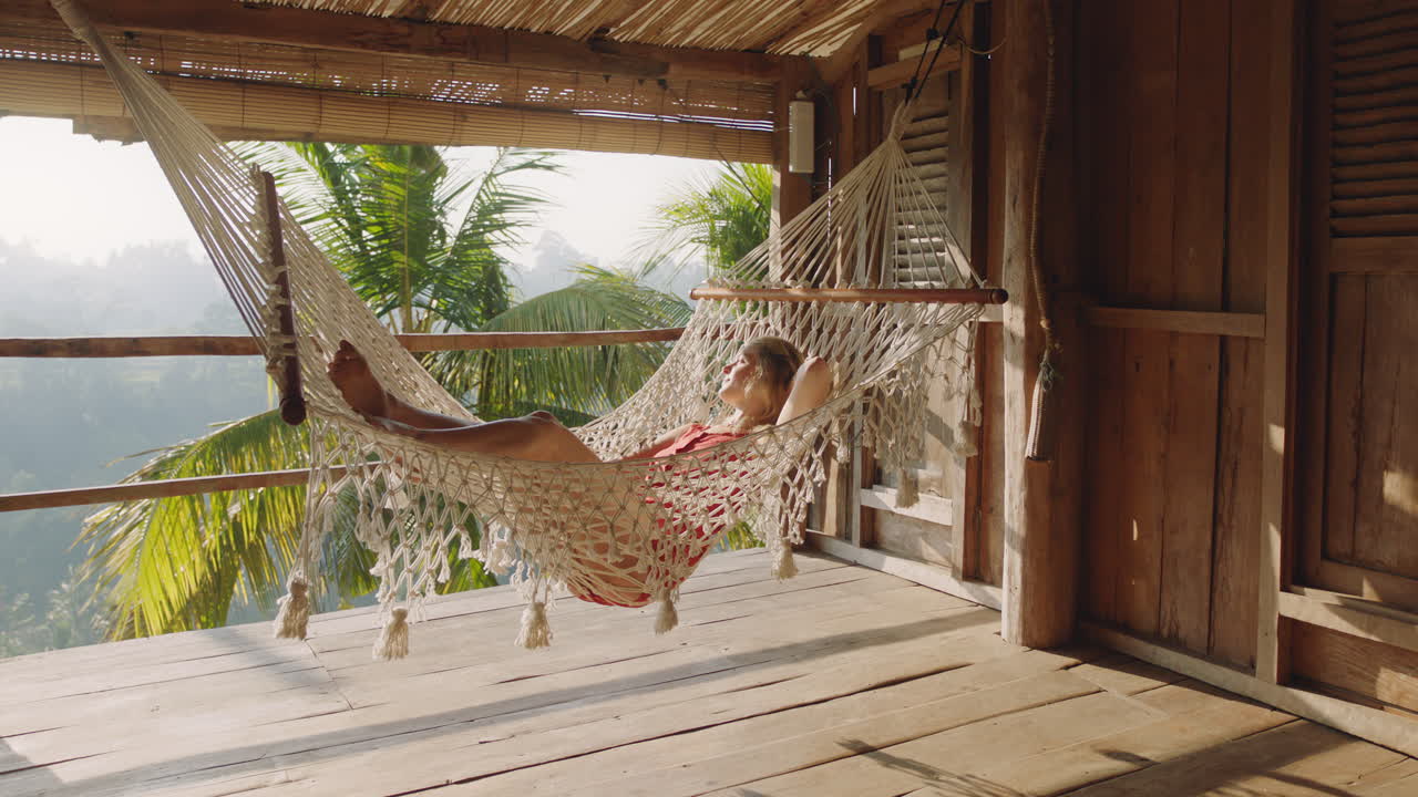 hermosa mujer en hamaca disfrutando de un estilo de vida cómodo de vacaciones en un complejo vacacional balanceándose pacíficamente en un perezoso día de verano en una cabaña de paraíso tropical