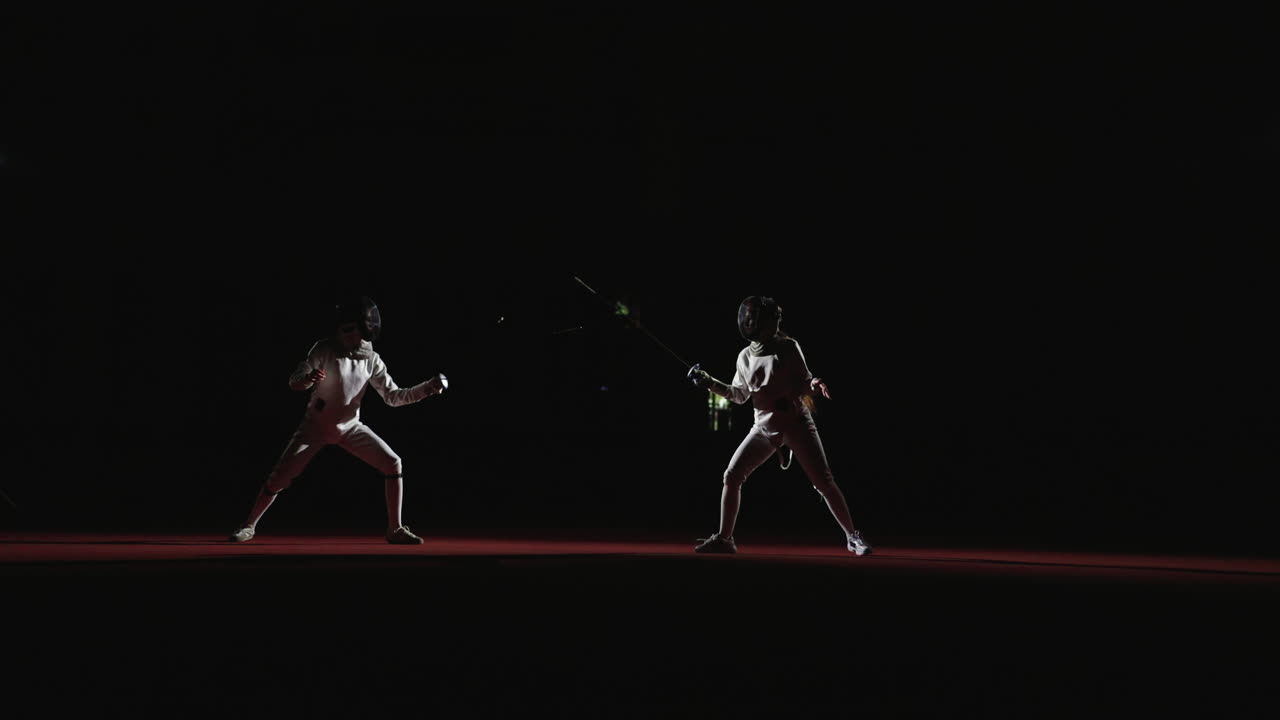 Two fencers compete in a match, one with a raised sword and the other in a defensive stance