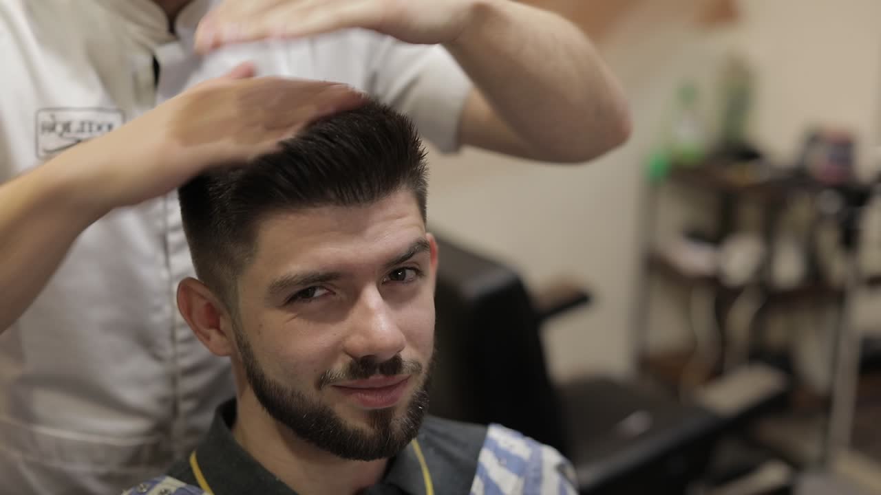 cliente con barba negra durante el corte de pelo en la barbería. novio, masculino