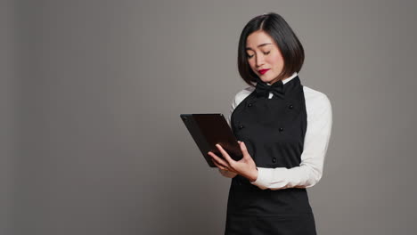 asian restaurant server checking all table reservations on tablet