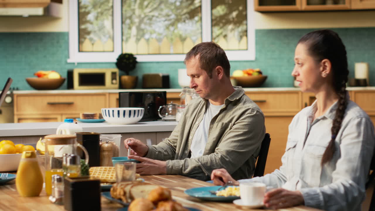 Smiling dad on tablet multitasking and chatting with his pre-teen daughter