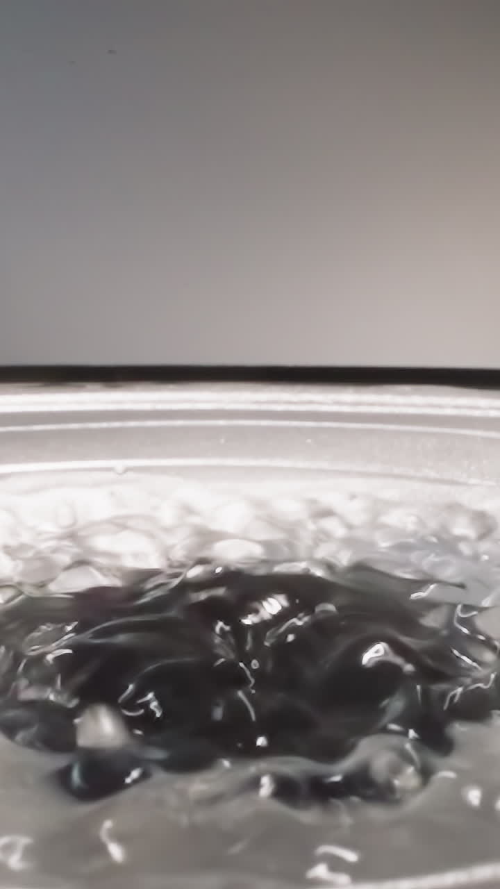 Liquid hyaluronic acid bouncing on operating loud speaker reflecting bright studio light. Slippery substance bubbling while music reproducing macro