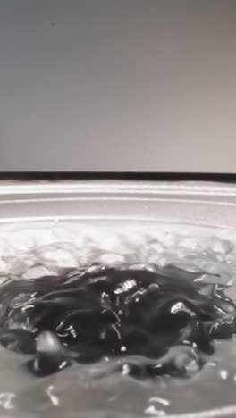 liquid hyaluronic acid bouncing on operating loud speaker reflecting bright studio light. slippery substance bubbling while music reproducing macro