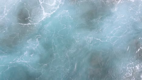 turbulent blue and green ocean waves splashing violently against a volcanic rock reef in canary islands, spain