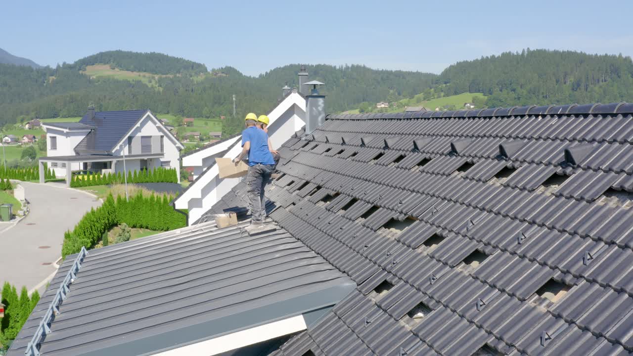 Aerial pullout of workers preparing house roof for solar panel installation