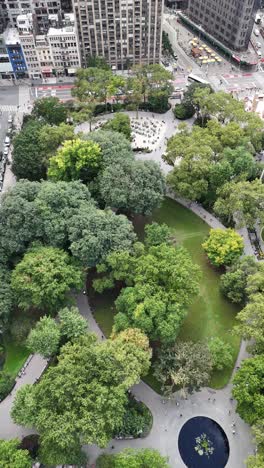a captivating vertical orientation drone circle shot of madison square park and e 25th street in new york city, showcasing the iconic greenery amid manhattan's vibrant skyline and bustling streets.