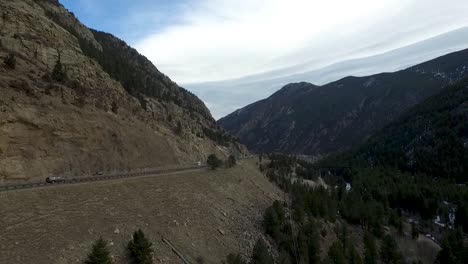 Antena-De-Drones-Volando-A-La-Derecha-Al-Lado-De-Una-Carretera-En-Un-Paso-De-Montaña