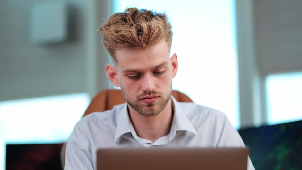 Young Businessman Sits Alone, Concentrated on Notebook Tasks in modern office