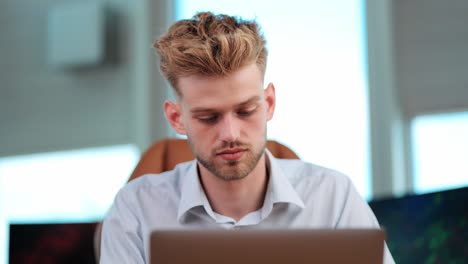 Young-Businessman-Sits-Alone,-Concentrated-on-Notebook-Tasks-in-modern-office