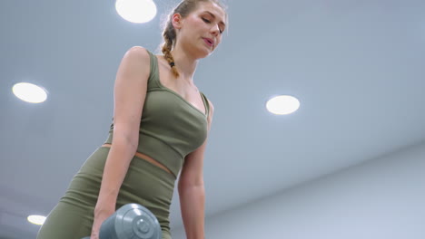 woman performs fitness exercise, focused and engaged, with lights above illuminating her movement, the calm atmosphere and bright lighting enhance her concentration during the workout