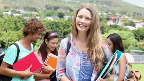 Pretty-student-smiling-at-camera-with-classmates-behind