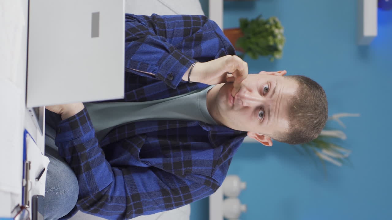 video vertical de un trabajador de oficina en casa mordiéndose las uñas mirando a la cámara.