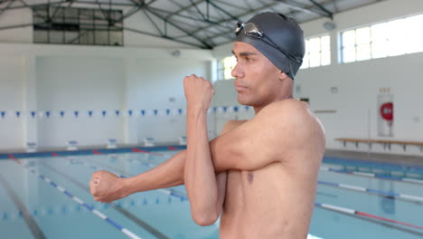 young biracial male athlete swimmer stretches before swimming