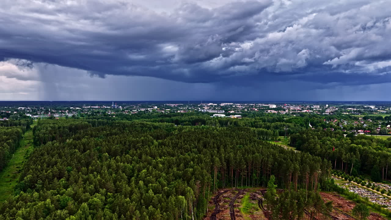 Waterspout falling from a dense cloud over a forest in background. Aerial