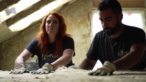 two restoration specialists meticulously handle a vintage textile in a well-lit space of an old building. they focus on preserving the fabric's integrity, showcasing their skills and techniques.