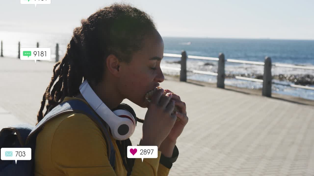 Woman eating sandwich on seaside, bubbles appearing and multiplying, highlighting social media buzz