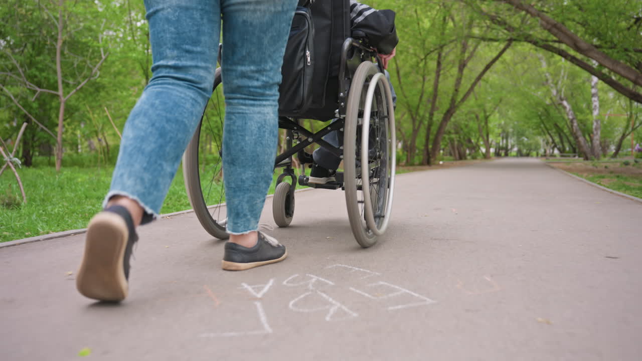 Close Shot Of Wheelchair Wheels And Caregiver, Rhythmic Progression Of Wheelchair And Caregiver Steps, Closeup Imagery Highlighting Synchronized Motion Between Wheelchair Wheels And Caregiver Steps