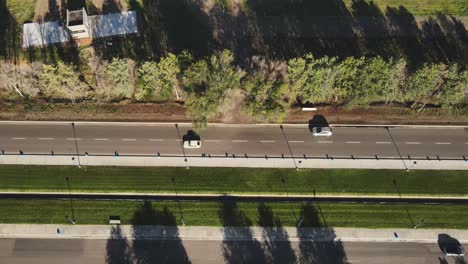 Aerial-view-over-countryside-road-and-then-camera-tilting-up-to-grass-farmland-fields-in-General-Roca,-Cordoba,-Argentina