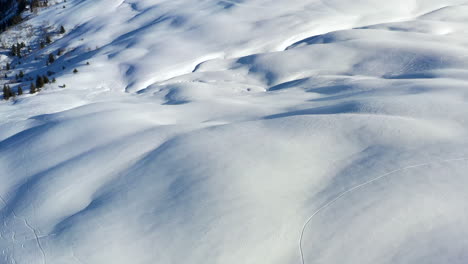 aerial view panning up from a snow field to reveal mont blanc and surrounding mountains in the sunshine, in the french alps in winter