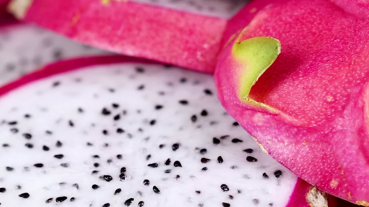Dettaglio macro della vivace buccia rosa e della polpa bianca di una pitaya affettata