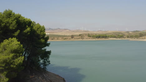 Kleine-Insel-Im-See-Caminito-Del-Rey,-Spanien,-Windkraftanlagen-In-Der-Ferne