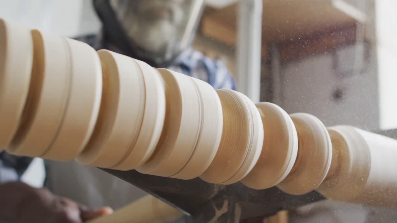 아프리카계 미국인 남성 목수 는 보호 헬 ⁇  을 착용 하여 목수 가게 에서 도자기 에서 나무를 돌리고 있다