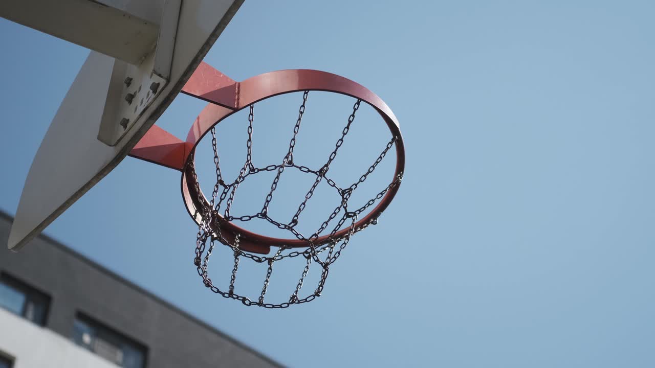 el baloncesto naranja golpea la canasta, la cancha de baloncesto en la calle, día soleado