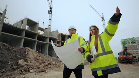 hombre y mujer están caminando en el sitio de construcción capataz y inspector de construcción femenino están comprobando el plan de construcción