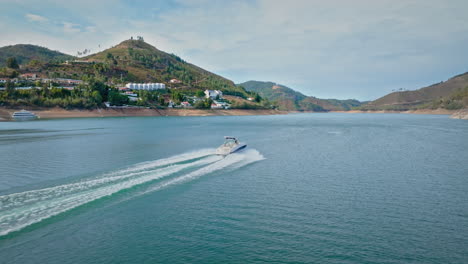 Kleines-Boot,-Das-Auf-Dem-Fluss-Segelt,-Neben-Einem-Kleinen-Touristischen-Dorf