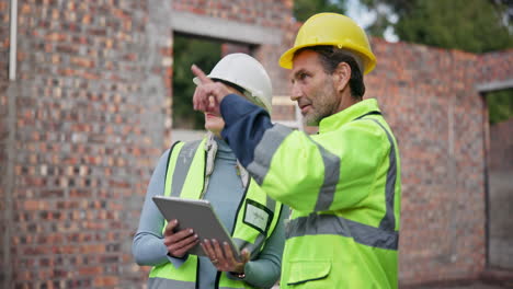 construction workers collaborating on a building site using a tablet