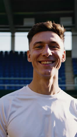 young man smiling in front of a stadium