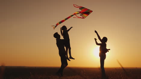 familia feliz jugando con una cometa al atardecer mamá papá e hija son felices juntos video 4k