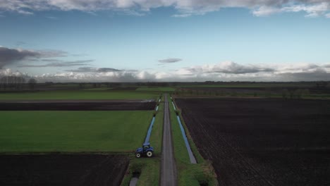drone flying backwards over dutch agricultural landscape, revealing a tractor.