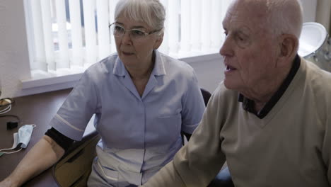 nurse and elderly man at desk