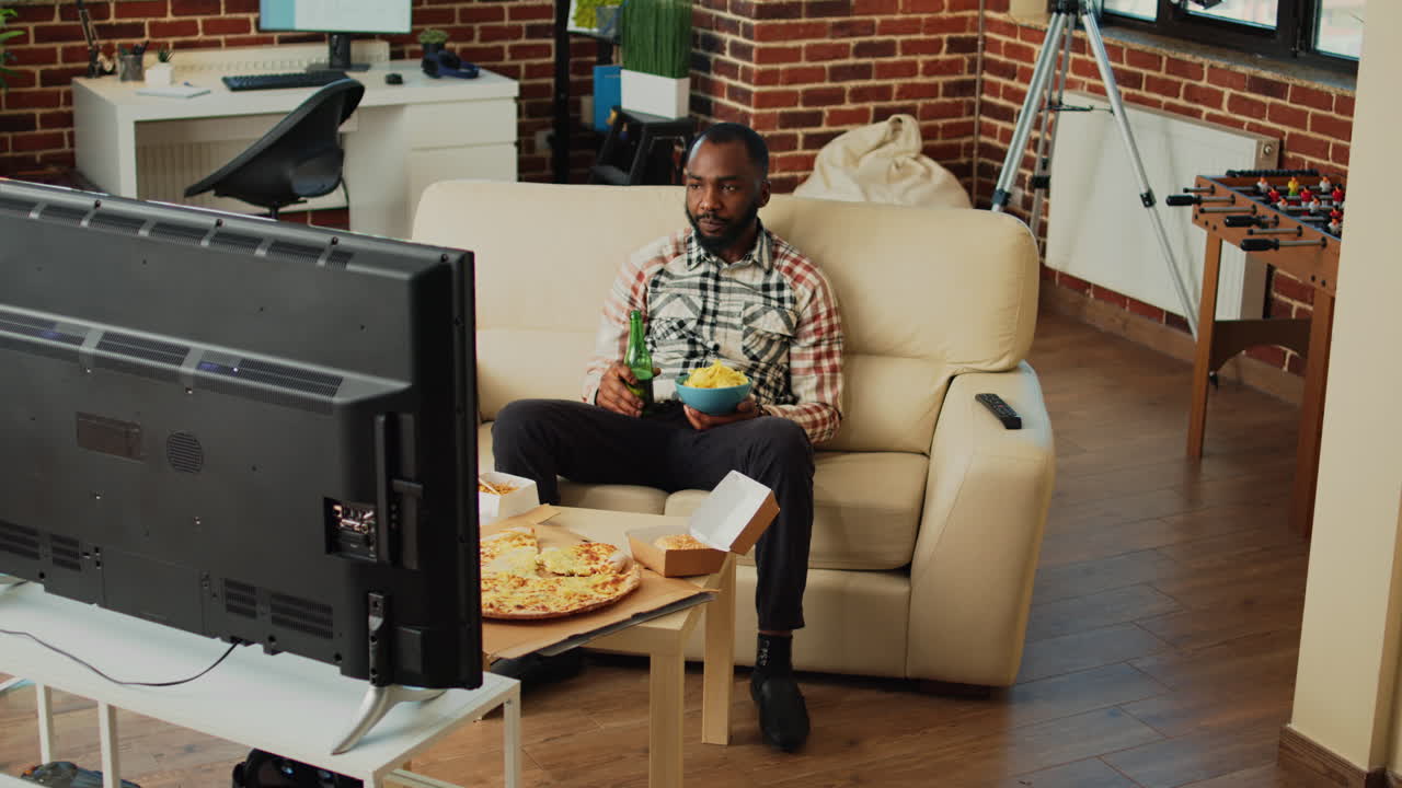 African american adult drinking beer and eating chips