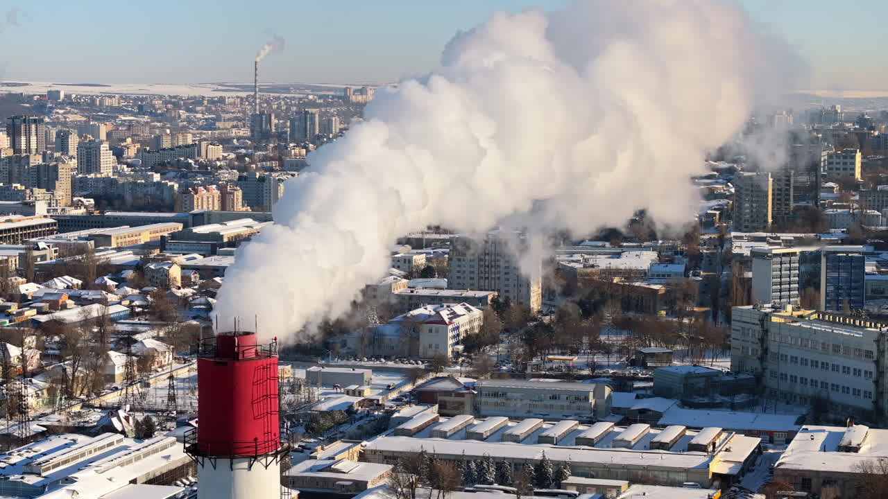 Aerial drone view of a working thermal power station in Chisinau city covered in snow. Steam and smoke coming from pipes. Moldova