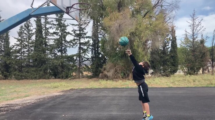 Un giovane ragazzo gioca a basket su un campo all'aperto a Kifisia, Grecia