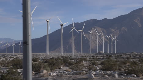 windmills pass by as seen from the passenger side of a car driving down the highway in california