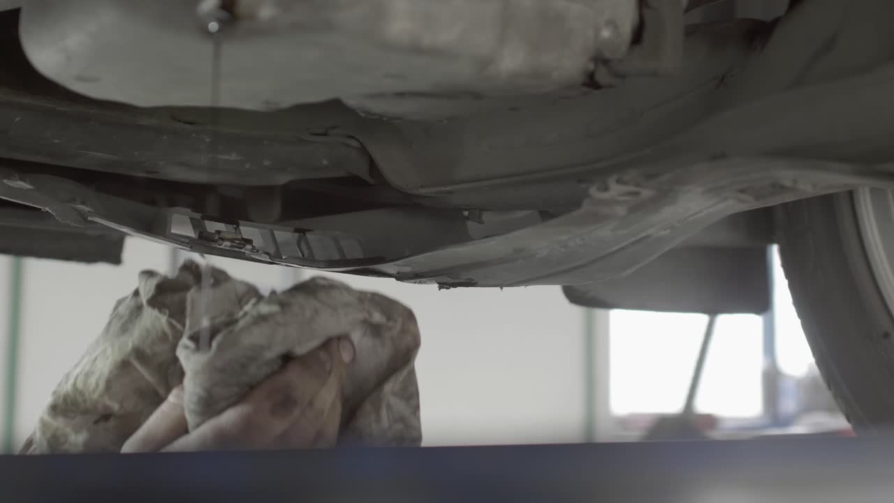 un mecánico usa trapos viejos para limpiar partes de un automóvil mientras realiza el mantenimiento