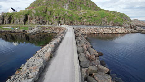 low aerial forwarding shot of a breakwater in nyksund, during summer in scandinavia, old fishing village