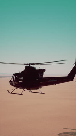 black helicopter flying over a desert