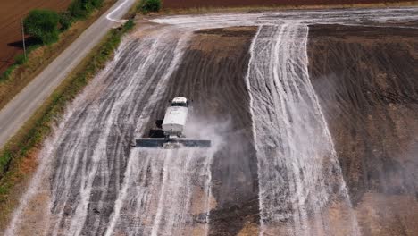 vista aérea de un tractor que conduce en el campo con rociadores que utilizan un sistema de supresión de polvo