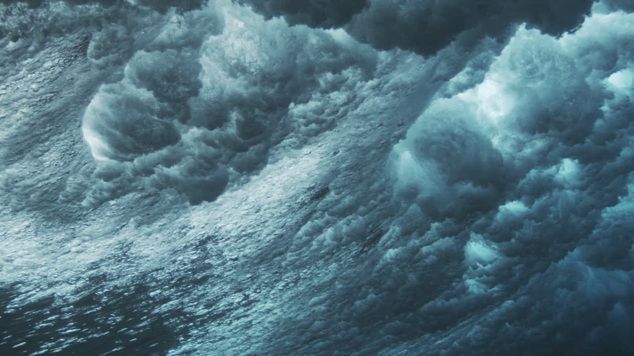 Breaking underwater wave with scattered bubbles and glowing light forming abstract ocean texture